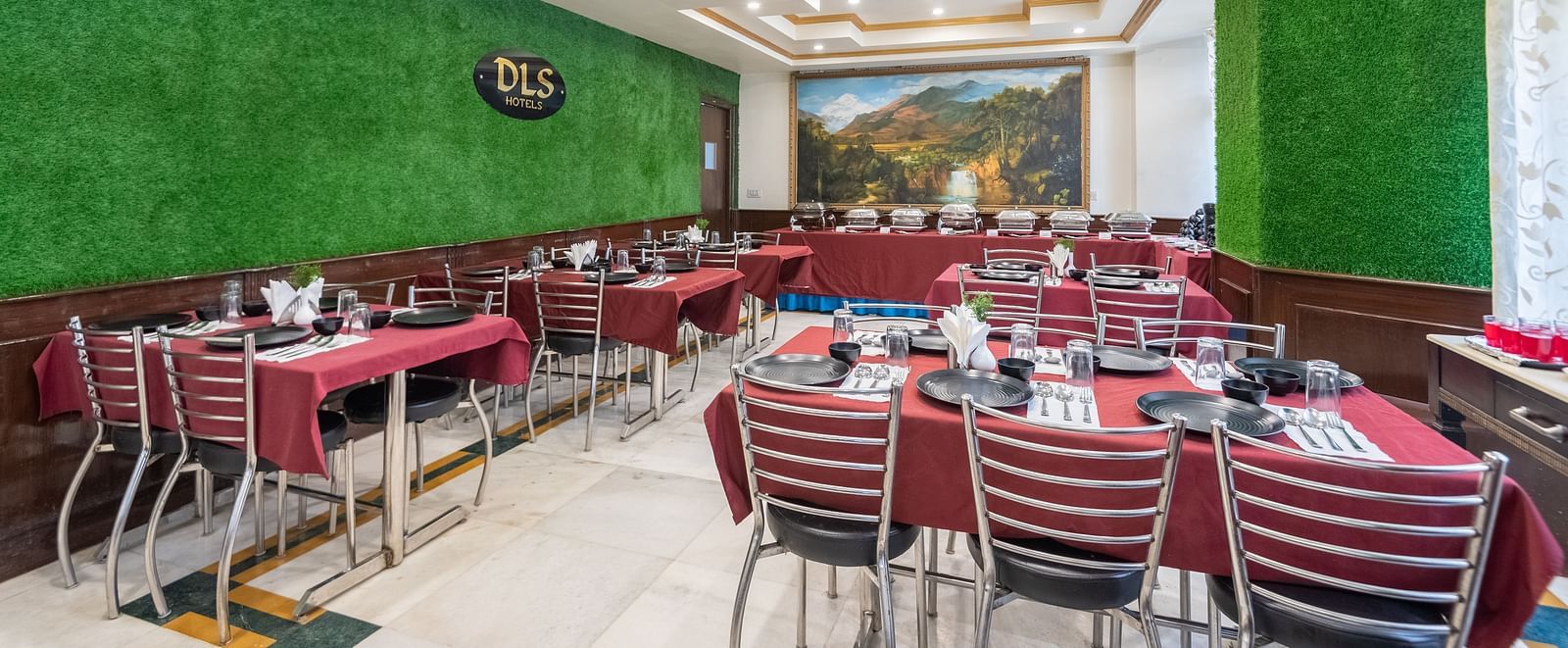 A spacious restaurant with a green wall, red tablecloths, and a scenic mural on one wall | DLS The Pearl