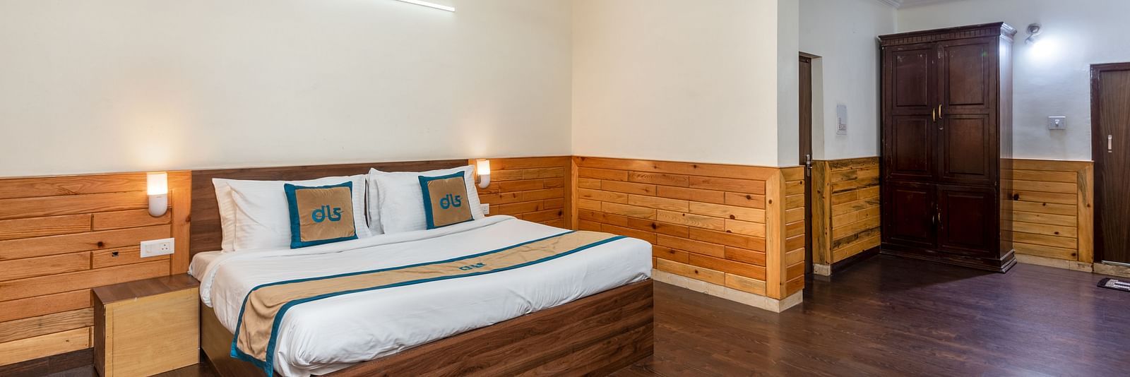 Image of well furnished room featuring a king size bed and a large open space with wooden flooring | DLS Anupam Resort, Dharamshala