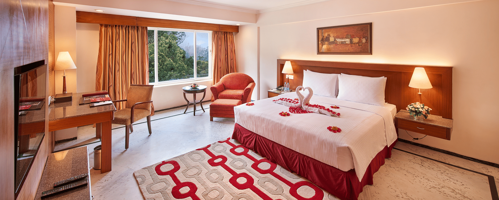 A room at Accord Highland Ooty with a double bed, a television and a work desk and chair