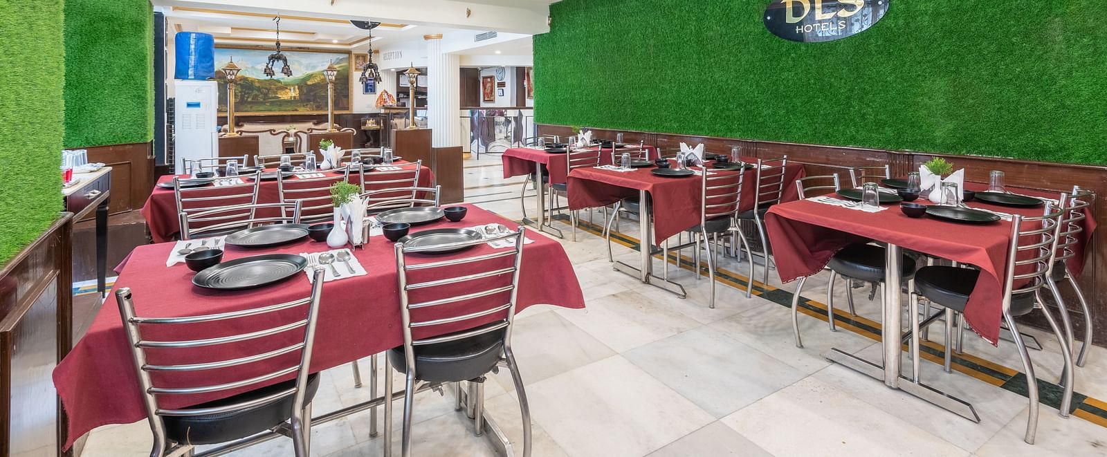 Image of dining area with red tablecloths, metal chairs, and a green wall | DLS The Pearl
