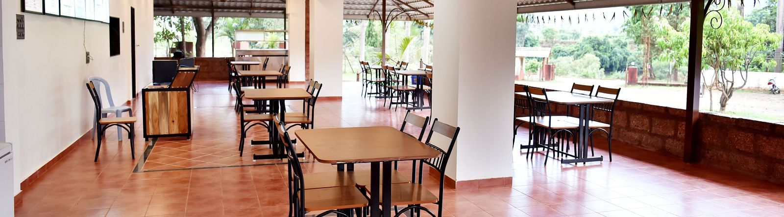 An interior view of the restaurant at Riverside Inn, featuring neatly arranged tables and chairs, with a ceiling fan overhead.
