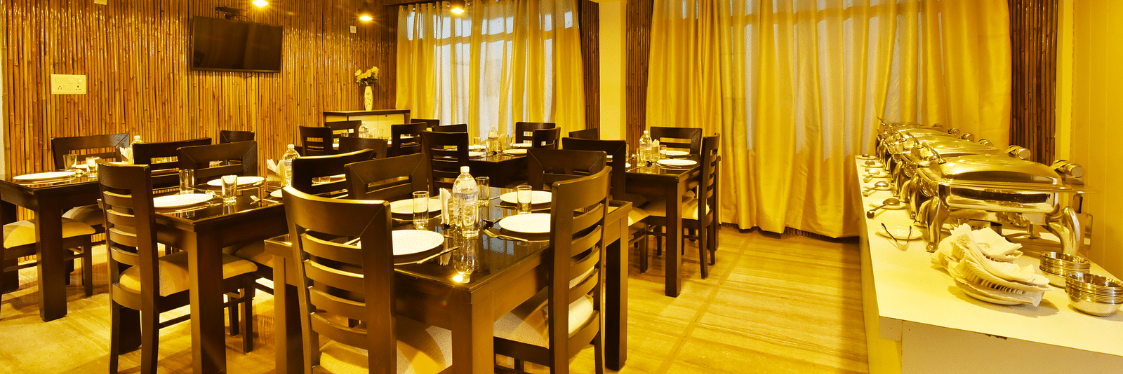 The bright and airy dining room at DLS Kapoor Resorts Manali offers a welcoming space for guests to enjoy their meals.