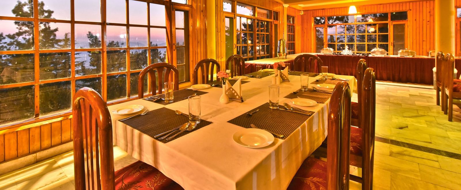 Restaurant with large windows offering scenic views at DLS Hillcrest Resort, Shimla.