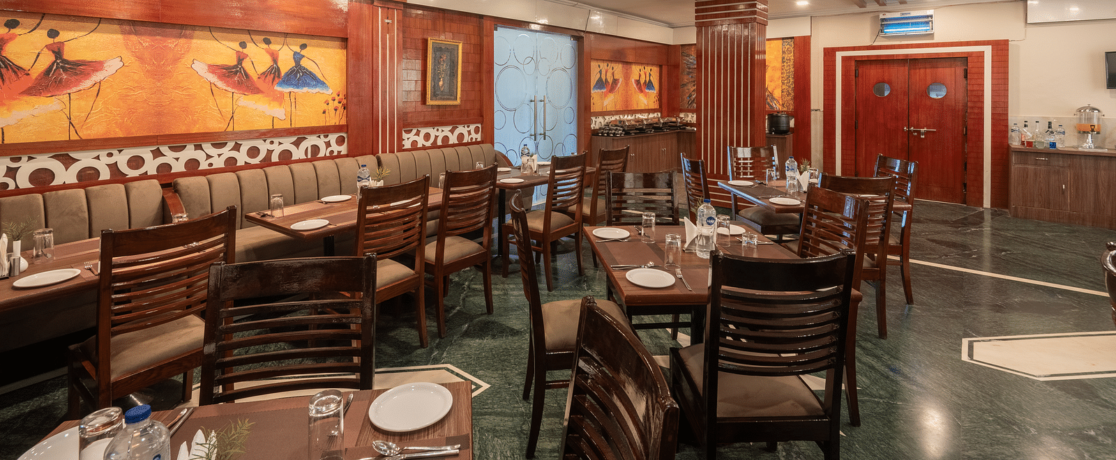 Dining area with colourful paintings on the side walls at DLS Park Grace, Haridwar.