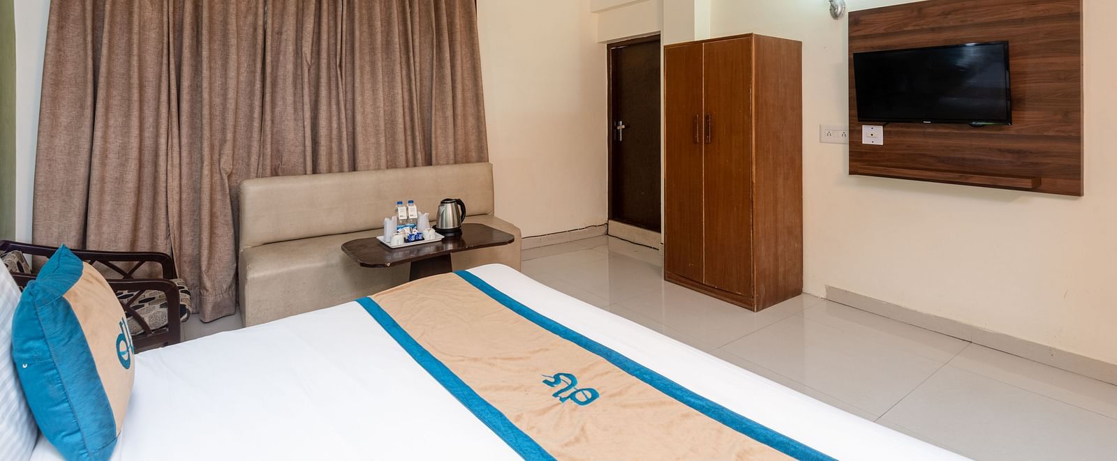 close up image of a bed in a room that is also featuring a television and a wardrobe | DLS Anupam Resort, Dharamshala