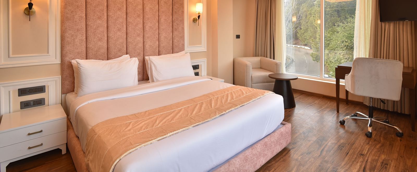 A modern bedroom with large windows that provide spectacular views of the surrounding mountains and lush greenery. The room features stylish furnishings and soft lighting.