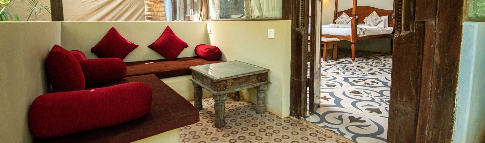 Cosy seating area in a rustic-style room with wooden elements and glass walls at De Soul Santé, Morjim.