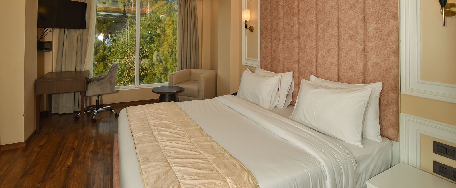  A bright and spacious hotel bedroom with a large bed, soft lighting, and large windows offering scenic mountain views.