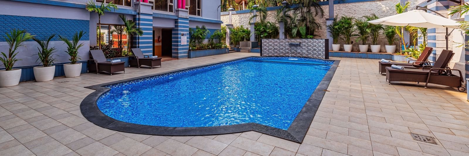 Outdoor swimming pool surrounded by the resort’s vibrant buildings, with poolside seating and lush greenery creating a refreshing leisure space.