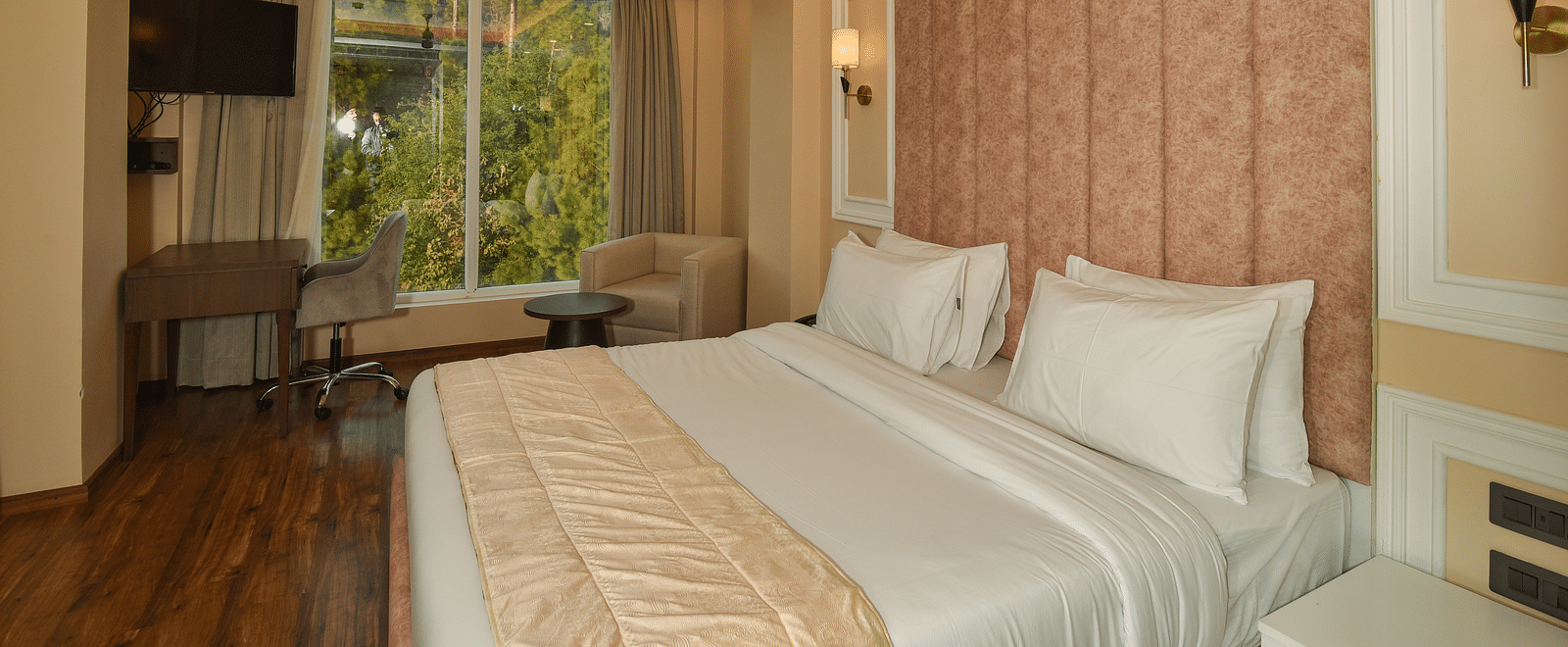  A bright and spacious hotel bedroom with a large bed, soft lighting, and large windows offering scenic mountain views.