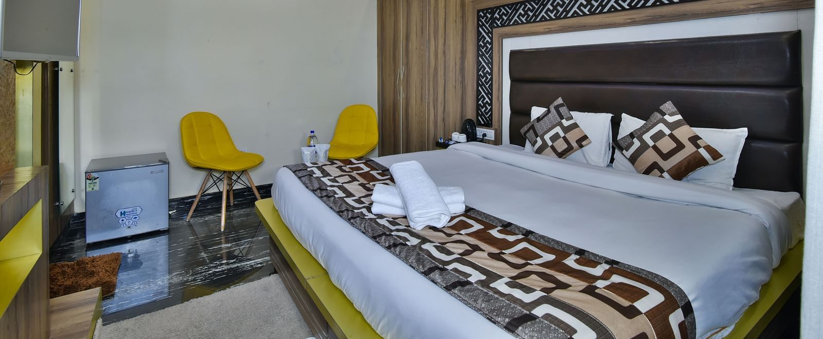 A Deluxe Room at DLS Dalhousie Valley Resort with a  king size bed and two yellow chairs