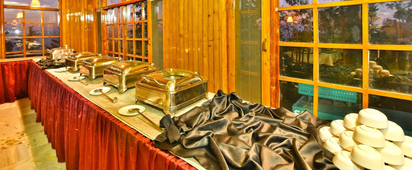 Buffet area with plates, bowls, and cutlery at DLS Hillcrest Resort, Shimla.
