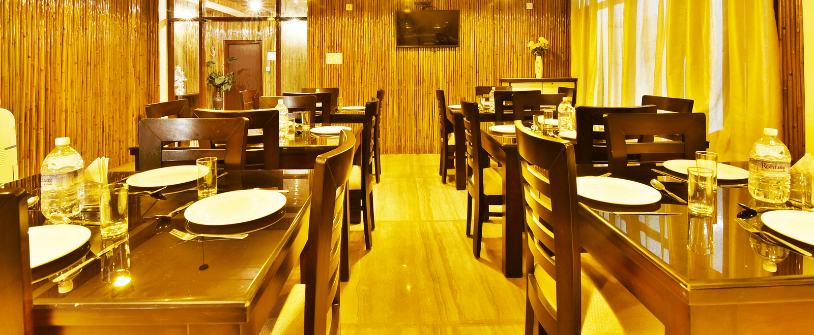A wide angle shot of the dining area at the resort with woodden tables and chairs | DLS Kapoor Resort Manali