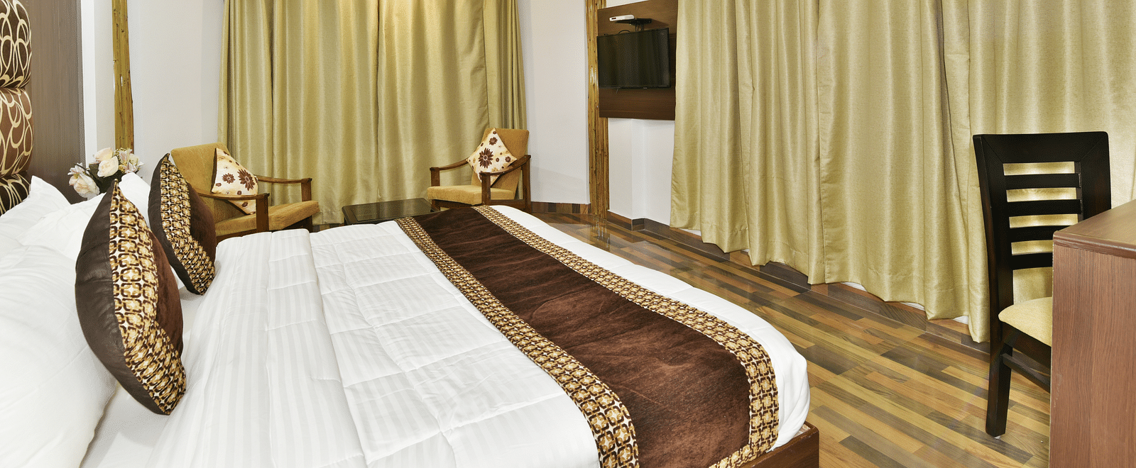 A close up shot a large room featuring king size bed, a side table and expansive windows with curtains | DLS Kapoor Resort Manali