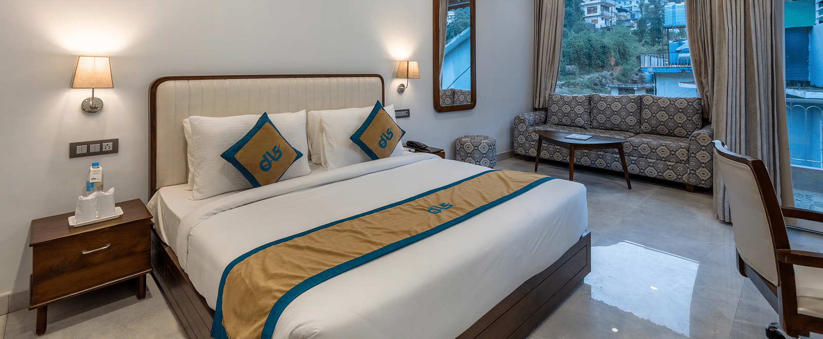 A Deluxe Non view room at DLS Spring Valley resort  Dharamshala featuring a  king bed, table, chairs and a big window