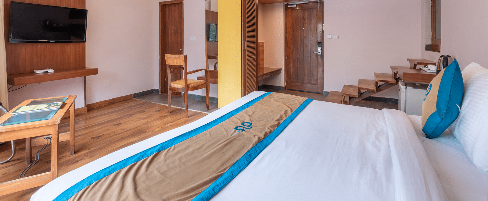 Side view of Luxury Cottage at DLS Spring Valley Resort Dharamshala featuring a king size bed, table, TV, and staircase