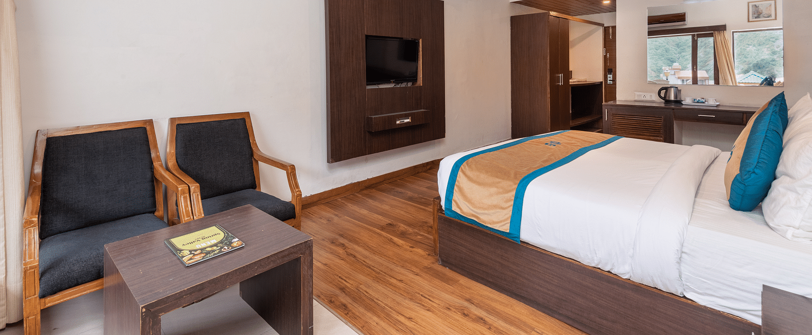 A Premium Room at DLS Spring Valley Resort Dharamshala featuring a king size bed, TV and a chairs