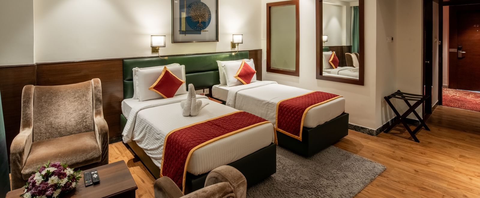 Twin bedroom with stylish decor, armchair, and framed artwork at Hotel Royal Regency Chennai