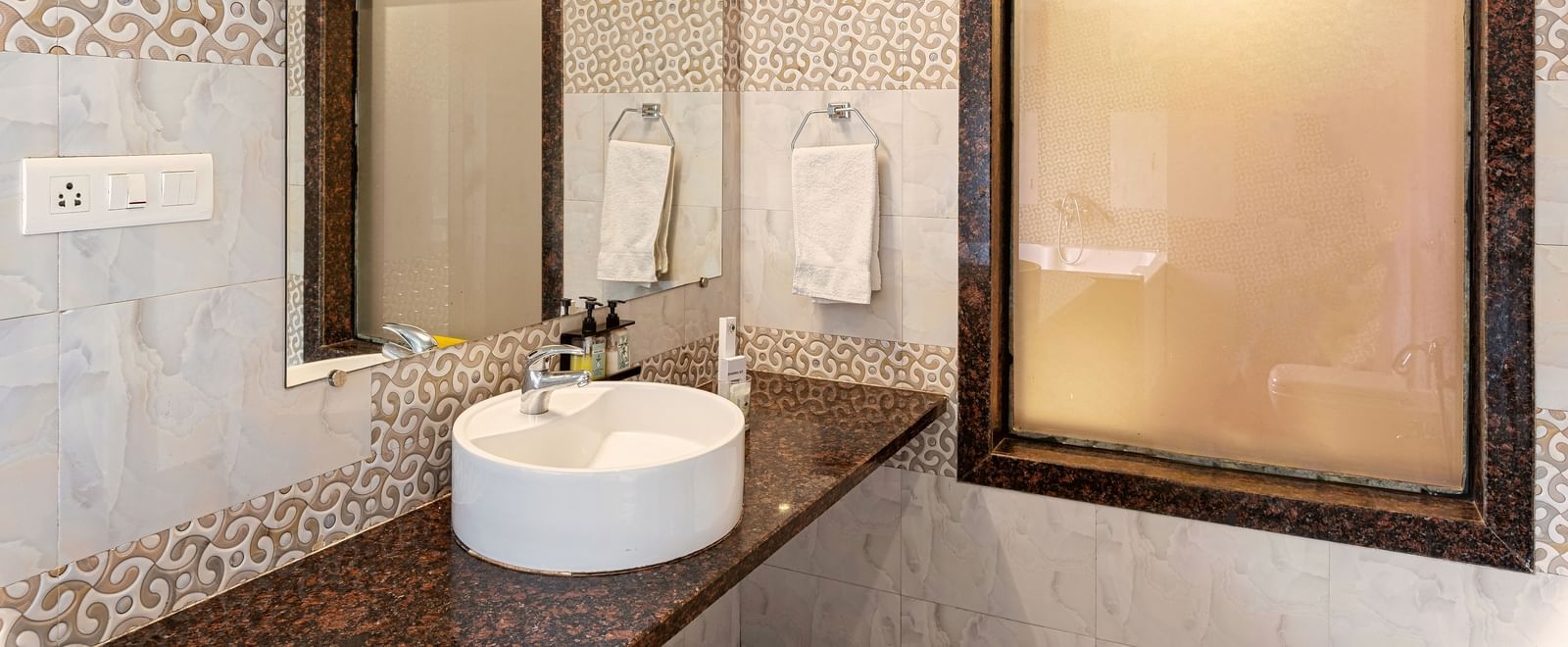Modern bathroom at Mayur Retreat featuring a vessel sink, patterned tiles, and a large framed mirror.