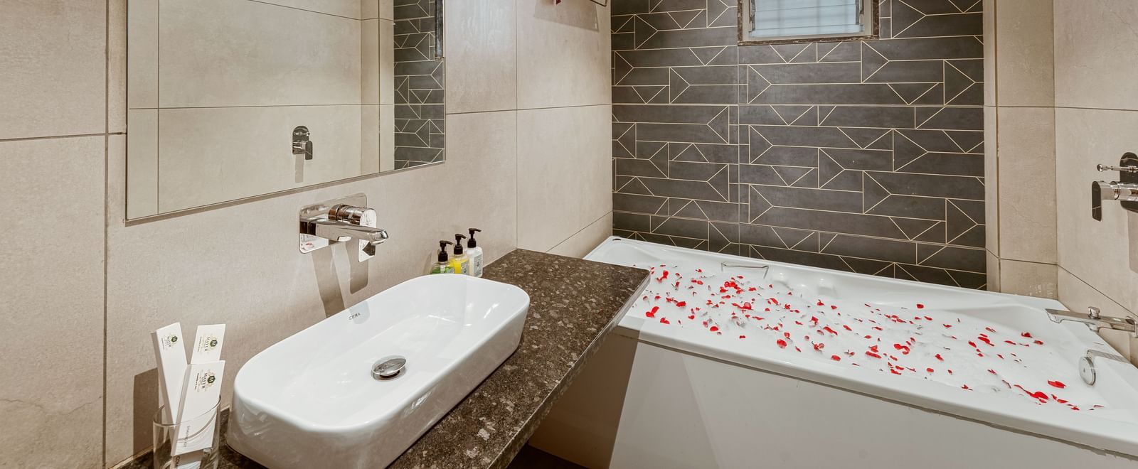 Modern bathroom at Mayur Retreat featuring a floral-decorated bathtub, sleek tiles, and a spacious layout.