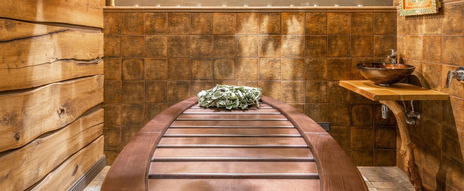 A spa room with wooden interiors showcasing a spa table, side table, and a photo frame.