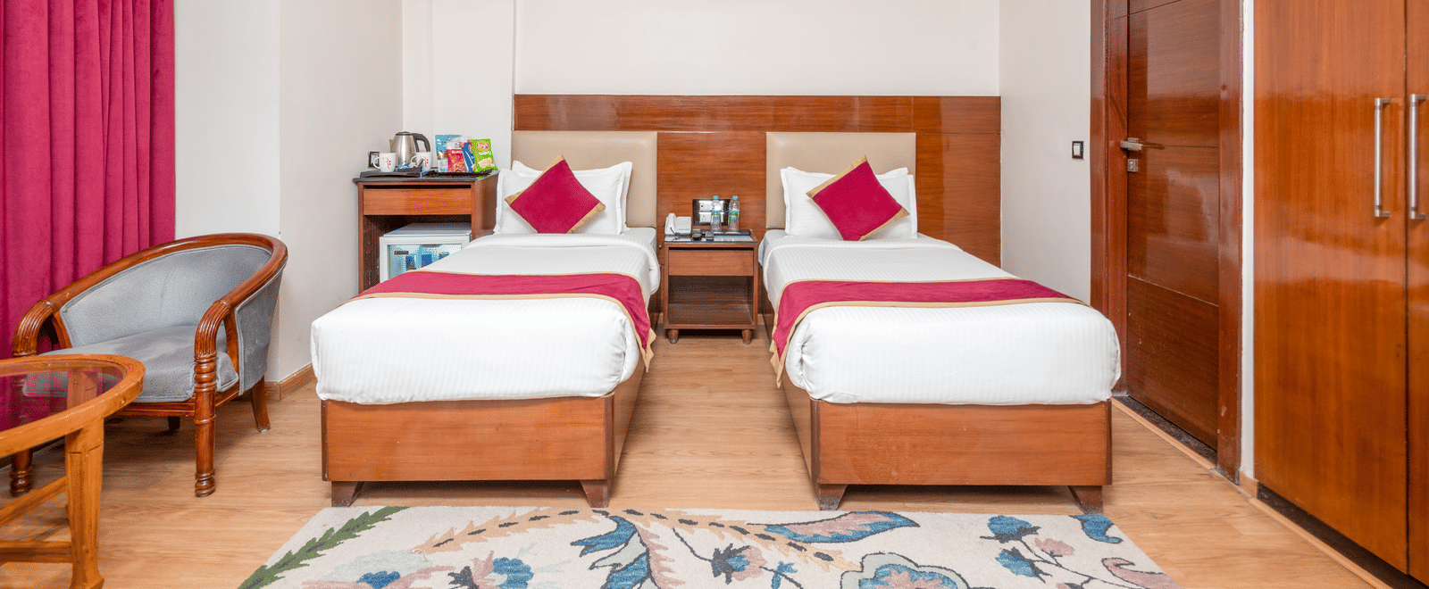 Twin bed room with pink curtains at DLS Hotels On The Ganges.