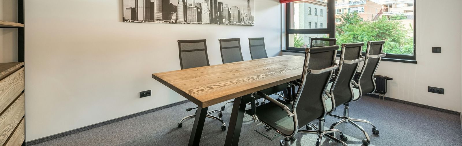 An image of a board room with chair and a table with three lights hanging from the ceiling