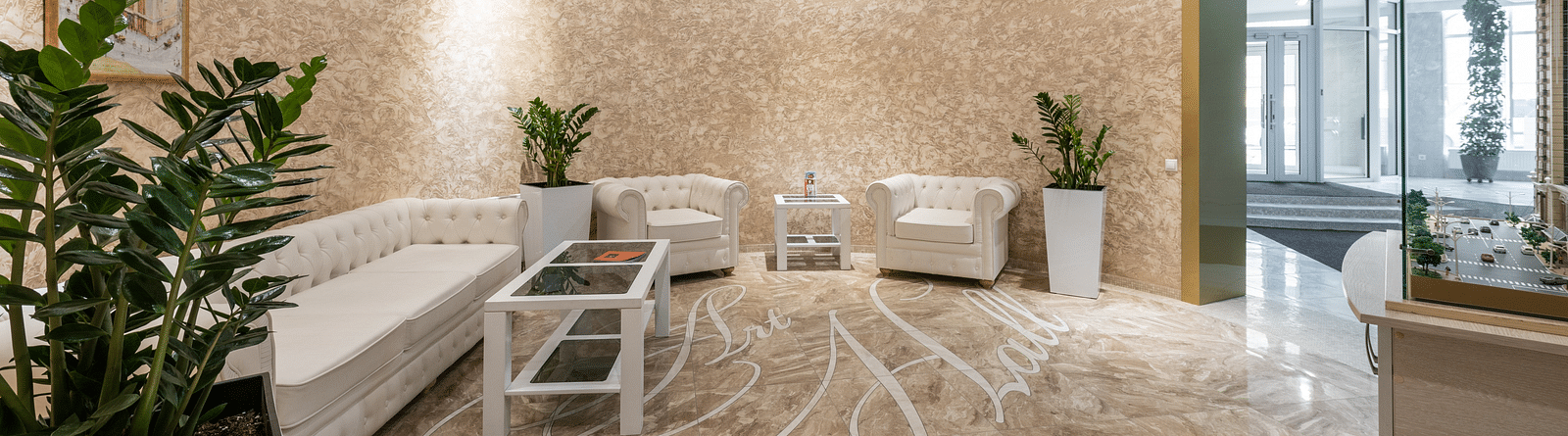 An elegant hotel lobby with ornate wooden furnishings, a large floral arrangement and a classic tiled floor