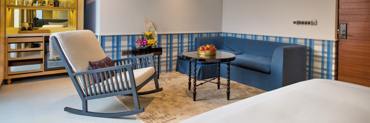 Blue rocking chair with matching couch in the background and a round table 