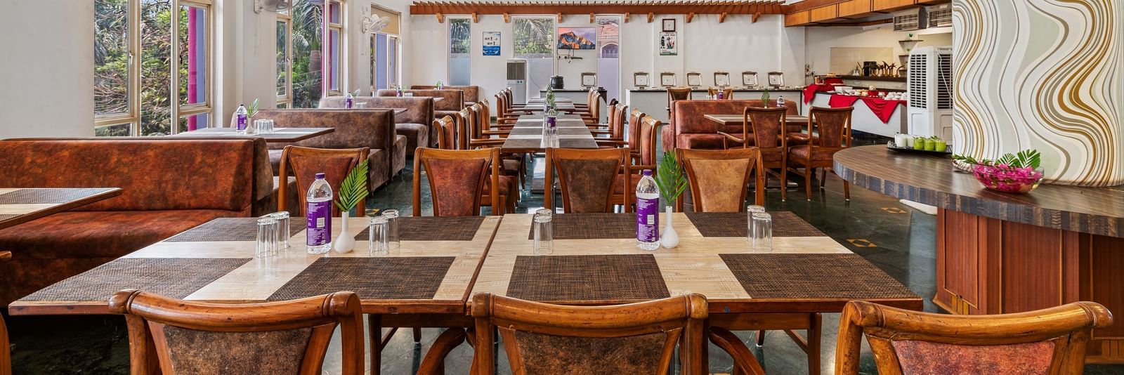 Indoor dining area with wooden furniture and colourful decor, part of The Darbar Restaurant at Mayur Retreat.