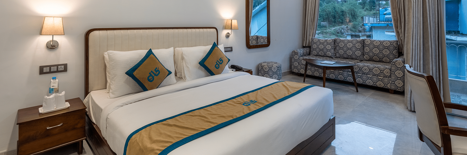 A Deluxe Non view room at DLS Spring Valley resort  Dharamshala featuring a  king bed, table, chairs and a big window