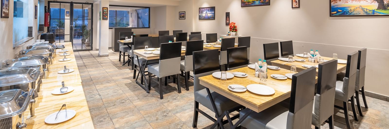 The indoor restaurant set up with chairs and tables along with a buffet table on the left at DLS Hotel Arihant, Haridwar