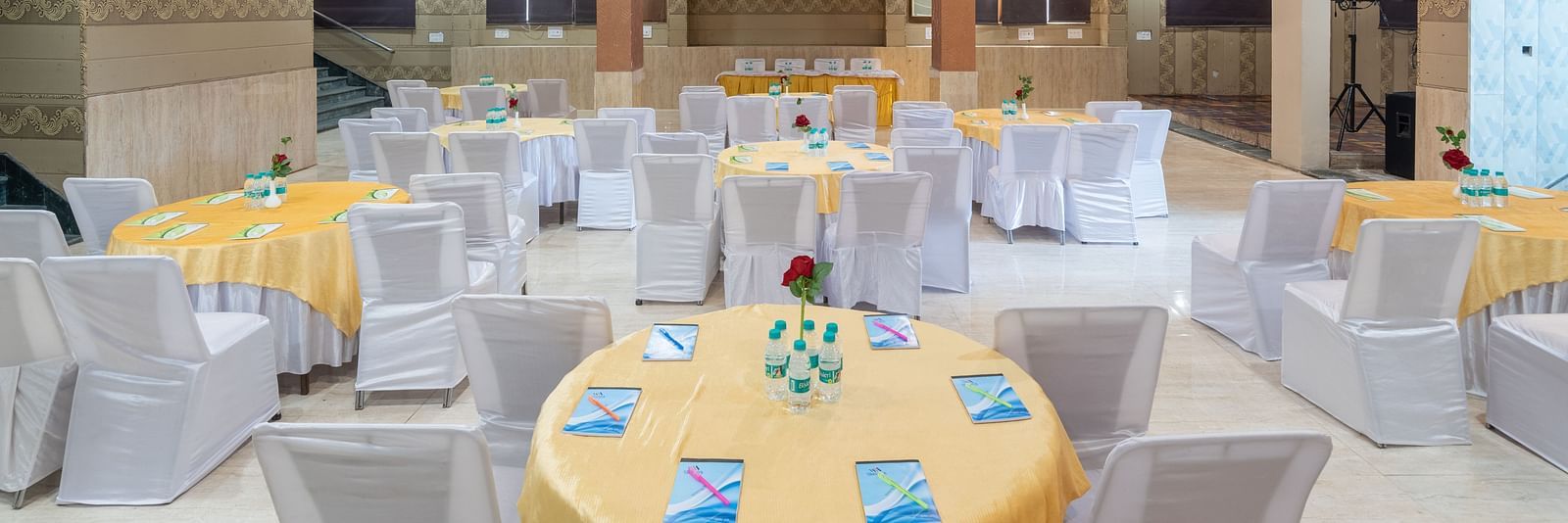 Banquet hall with round tables and chairs at DLS Park Grace, Haridwar.