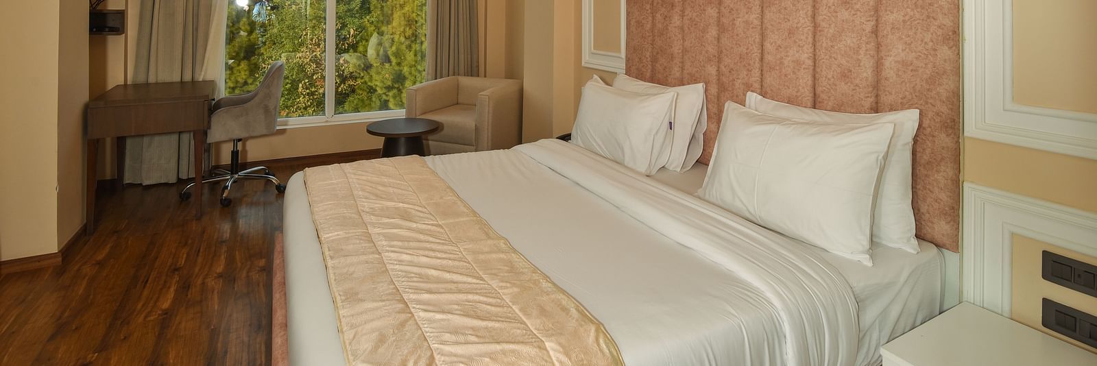  A bright and spacious hotel bedroom with a large bed, soft lighting, and large windows offering scenic mountain views.