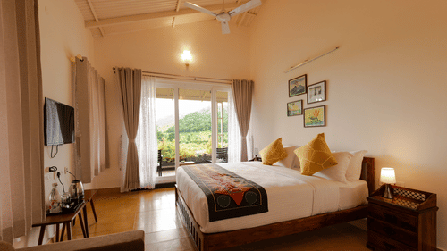 a double bed in front of a wall mounted tv in Bear Room - Ibex Resort, Kotagiri