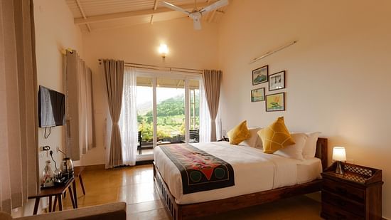 a double bed in front of a wall mounted tv in Bear Room - Ibex Stays & Trails, Kotagiri
