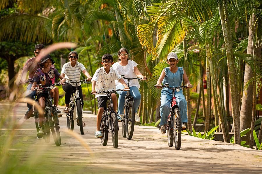 kids Cycling on a pathway next to coconut trees  - Ibex River Resort, Pollachi