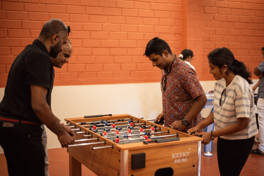 a group of people playing foosball inside the game room at Ibex River Resort, Pollachi