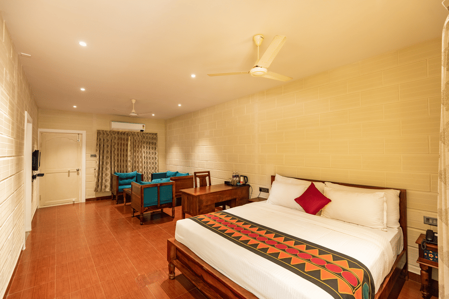 A double bed, sofas and a fan on the ceiling inside the suite at Ibex River Resort, Pollachi.