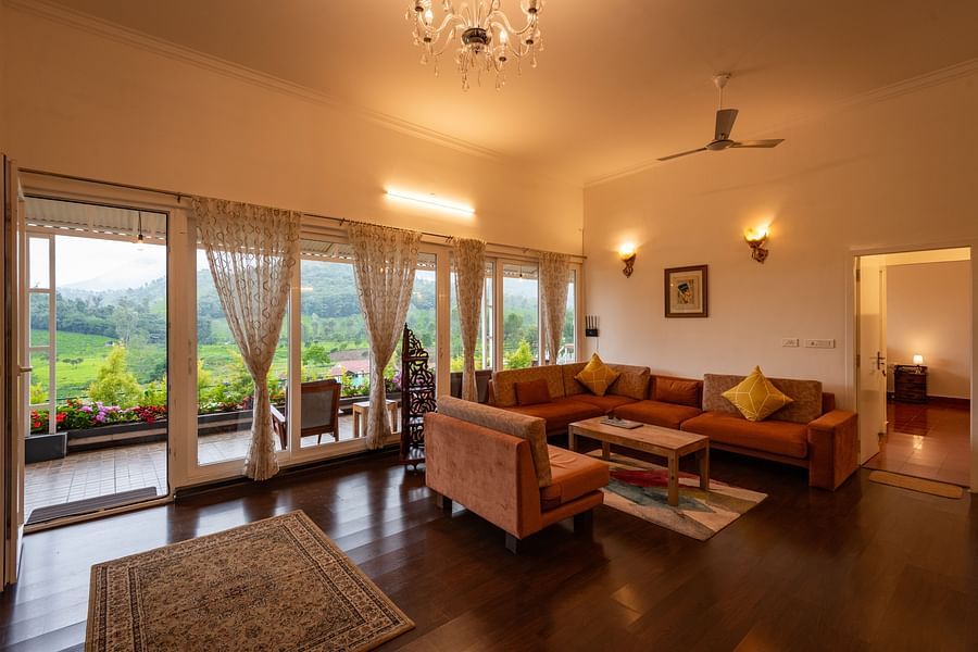 Main House Living Area with sofa and coffee table in the centre and floor to ceiling windows - Ibex Stays & Trails, Kotagiri