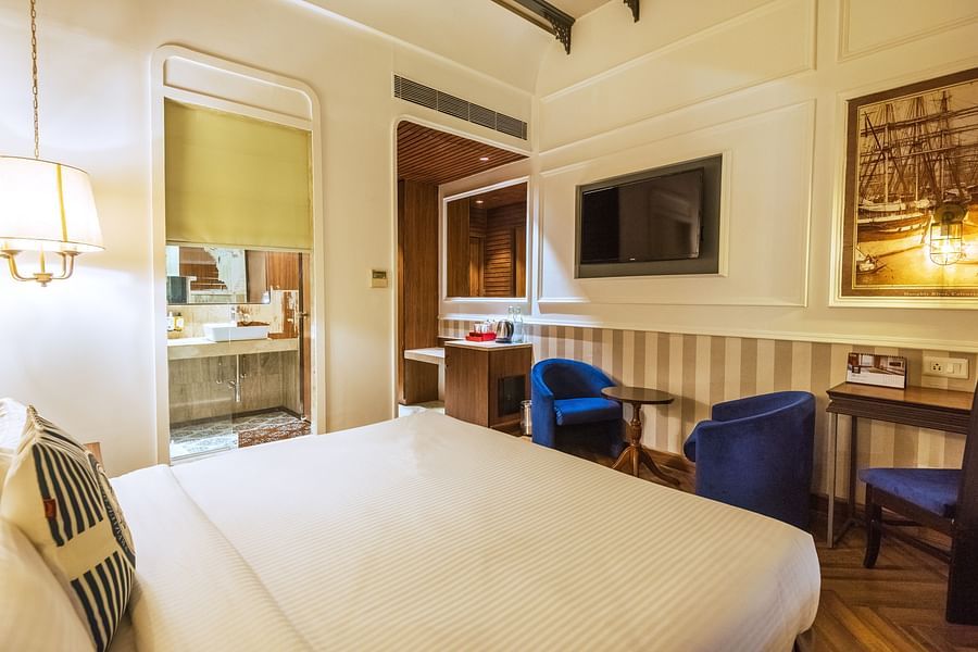 a well made bed with blue chairs opposite to the bed - polo floatel kolkata
