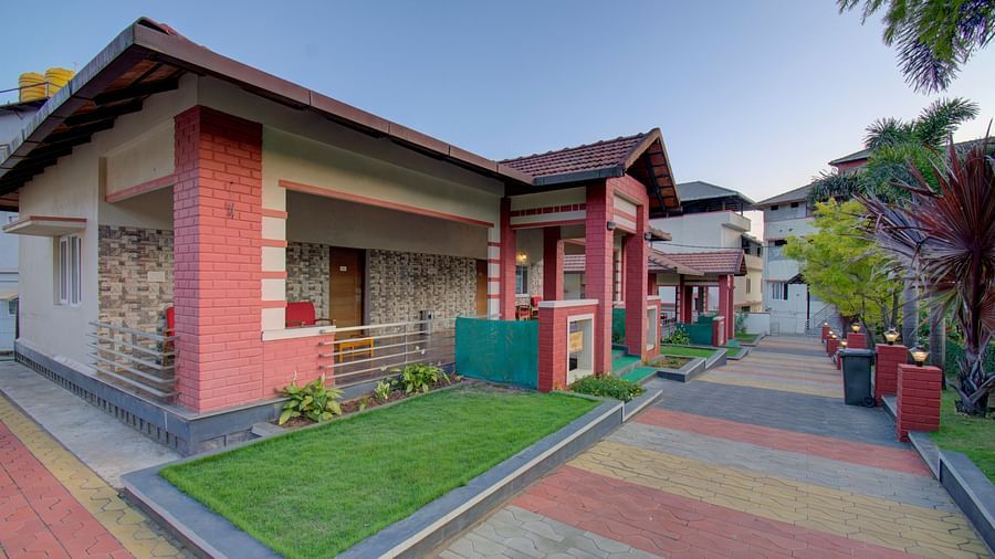 A perspective of the pathway and building design at Woodstock Resorts, Coorg with a garden area.