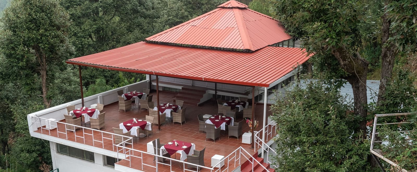 A charming outdoor restaurant at DLS Tehri Club Resort with a scenic view of the surrounding hills.