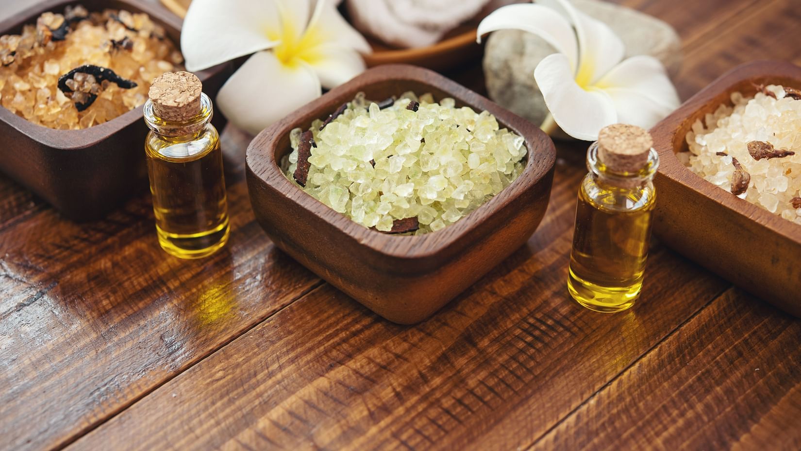 sea-salt-towels-aroma-oil-bottles-flowers-vintage-wooden-background