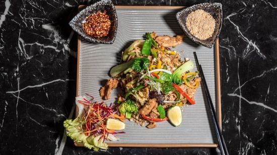 Gourmet Asian salad on a marble table at Asiatic Lounge, served with crisp greens, colourful vegetables, and two dipping sauces.