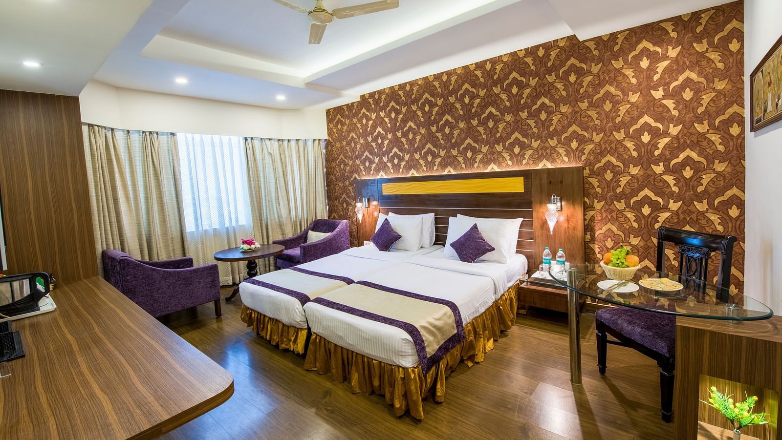 Side veiw of Grand Room witn bed and seating area and large windows on the side at Swosti Grand, Bhubaneswar