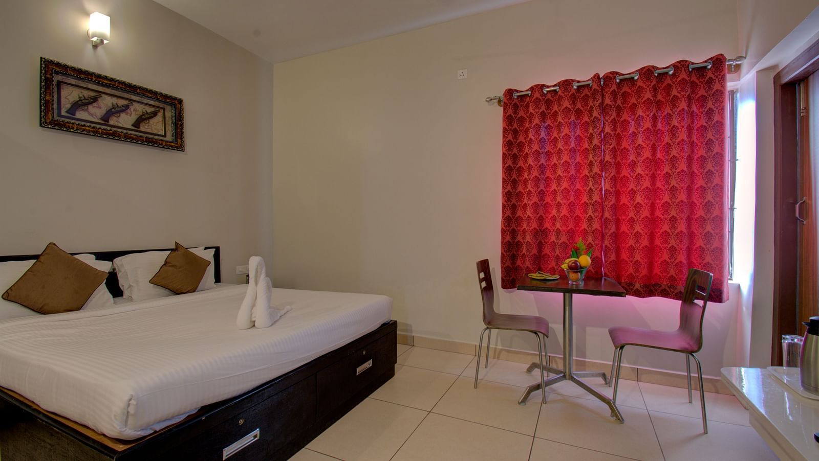 a Swan made of towel on a huge bed, table, chairs, and windows with curtains | Superior Room | Woodstock Resorts, Coorg