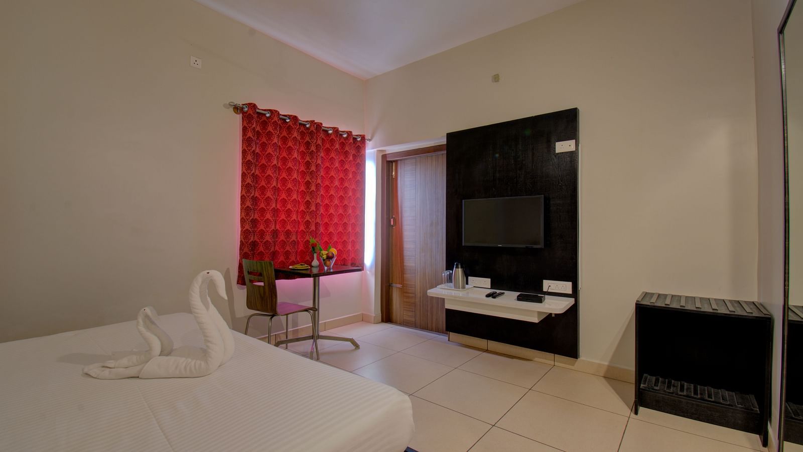 A bedroom with a bed, TV, curtained window, cabinet | Superior Room | Woodstock Resorts, Coorg