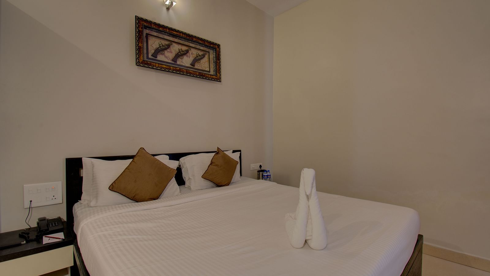 A bedroom with a bed, a side table and a wall art | Superior Room | Woodstock Resorts, Coorg