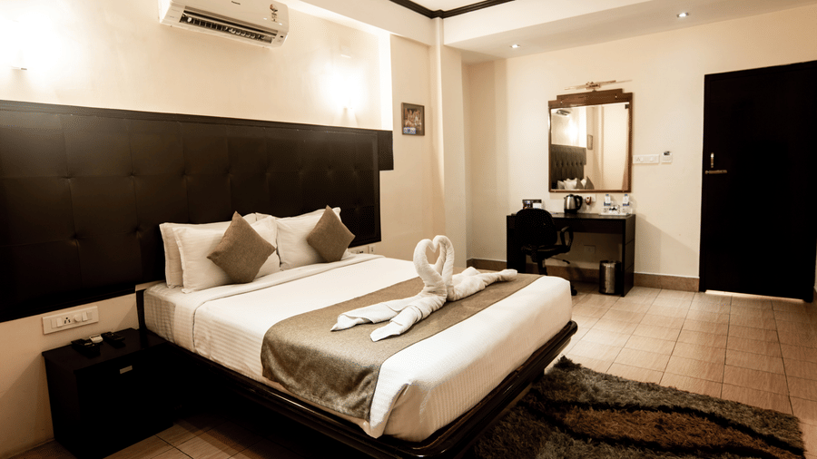 The Executive Suites in Polo Hotels, Tura, with a large bed, pillows, bedspreads, and a wall mounted air-conditioner.